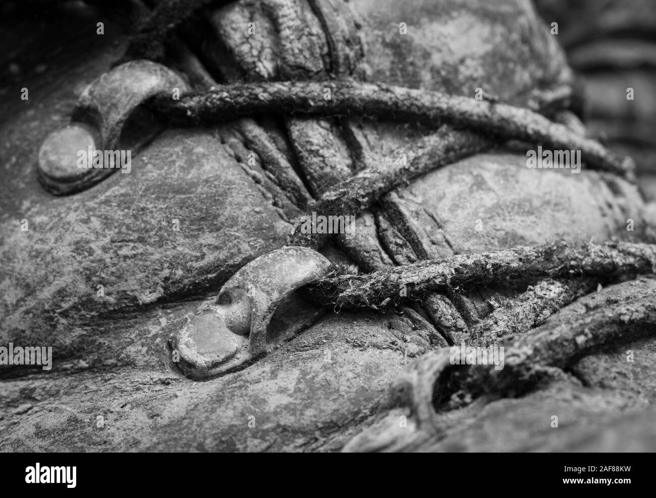Noir & blanc, close-up shot de lacets boueux et œillets sur paire de vieux bottes de marche. Métaphore camping, randonnée / trekking, vie en plein air Banque D'Images