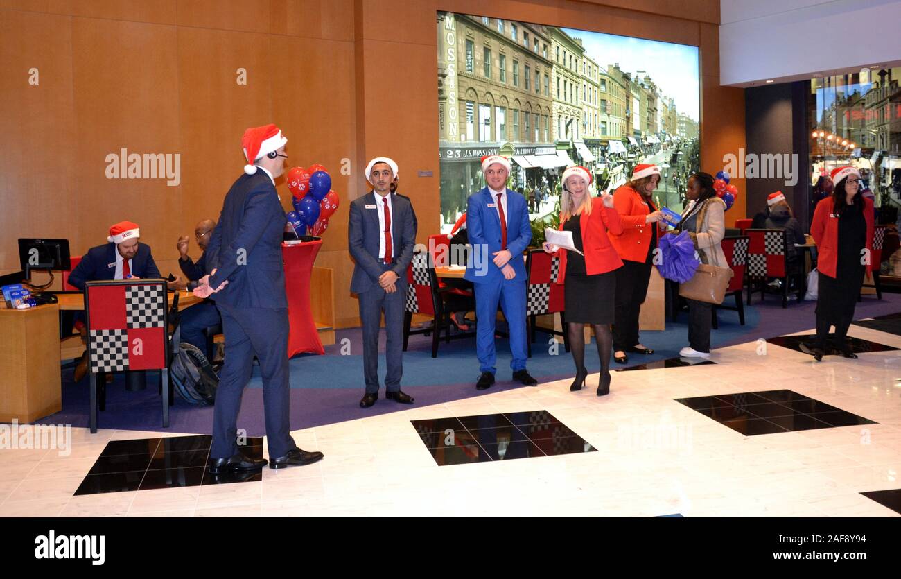 Le 13 décembre, 2019, Metro Bank ouvre une nouvelle succursale à Market Street, Manchester, Royaume-Uni. Personnel porte des chapeaux de Noël pour accueillir les clients. Banque D'Images