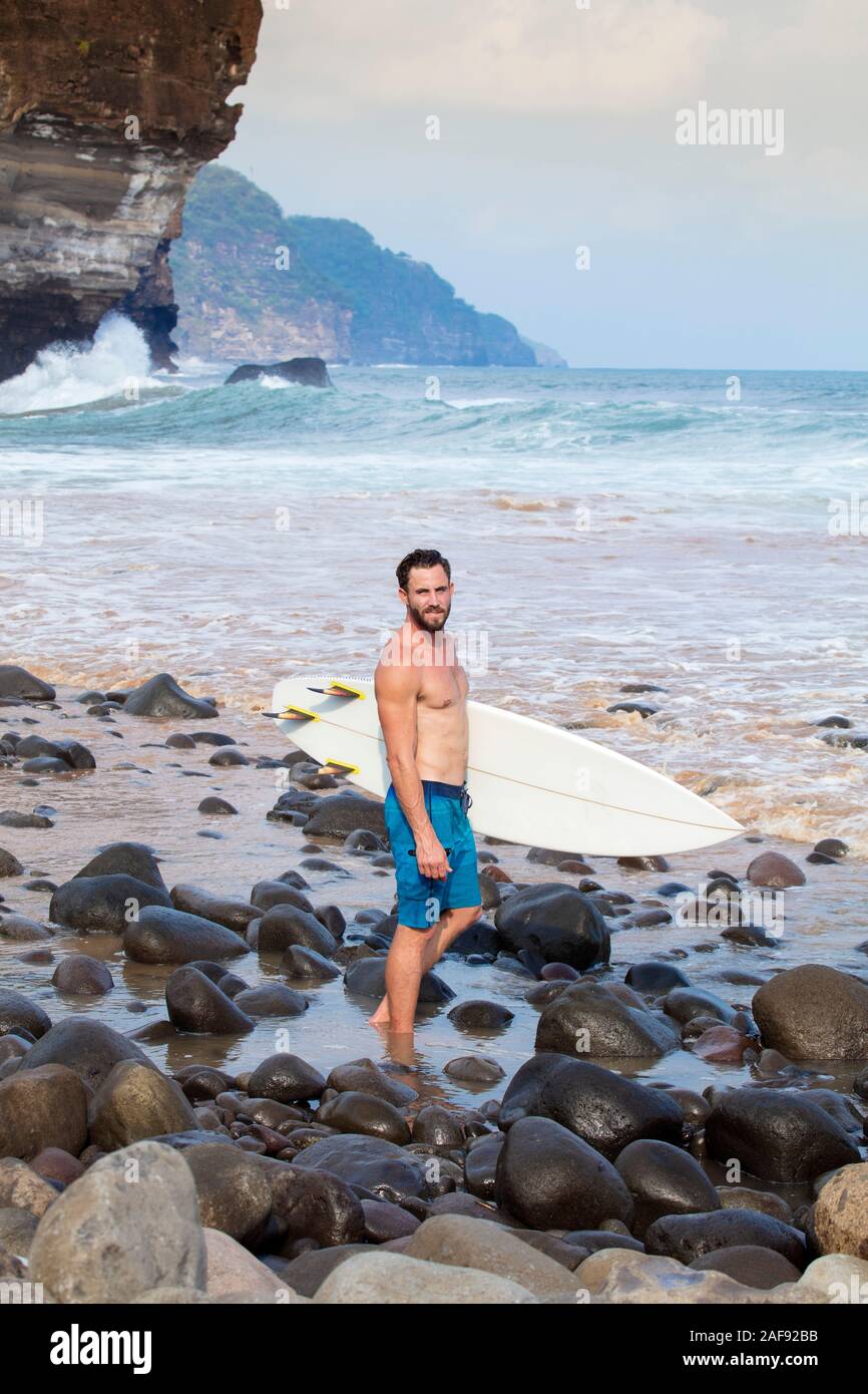 Un jeune surfeur sur une plage de la côte du Pacifique en El Salvador, en Amérique centrale Banque D'Images