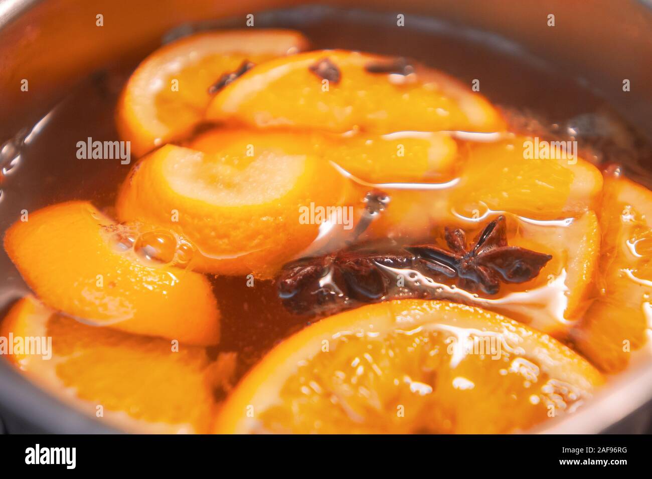 La préparation de boissons vin chaud avec des oranges et des épices. Les boissons de Noël faire bouillir dans le moule en métal. Glintwine de vin rose avec des agrumes, de girofle Banque D'Images