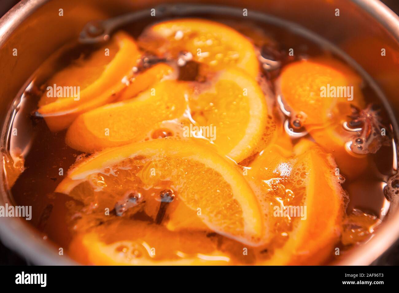 La préparation de boissons vin chaud avec des oranges et des épices. Les boissons de Noël faire bouillir dans le moule en métal. Glintwine de vin rose avec des agrumes, de girofle Banque D'Images