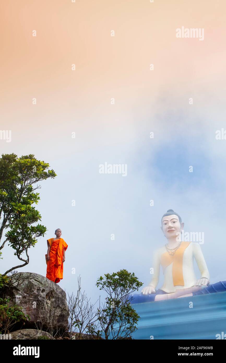 Un samanera ou moine novice debout devant une statue géante de la divinité locale Coucou Mao, la montagne de Bokor, Kampot, Cambodge Banque D'Images