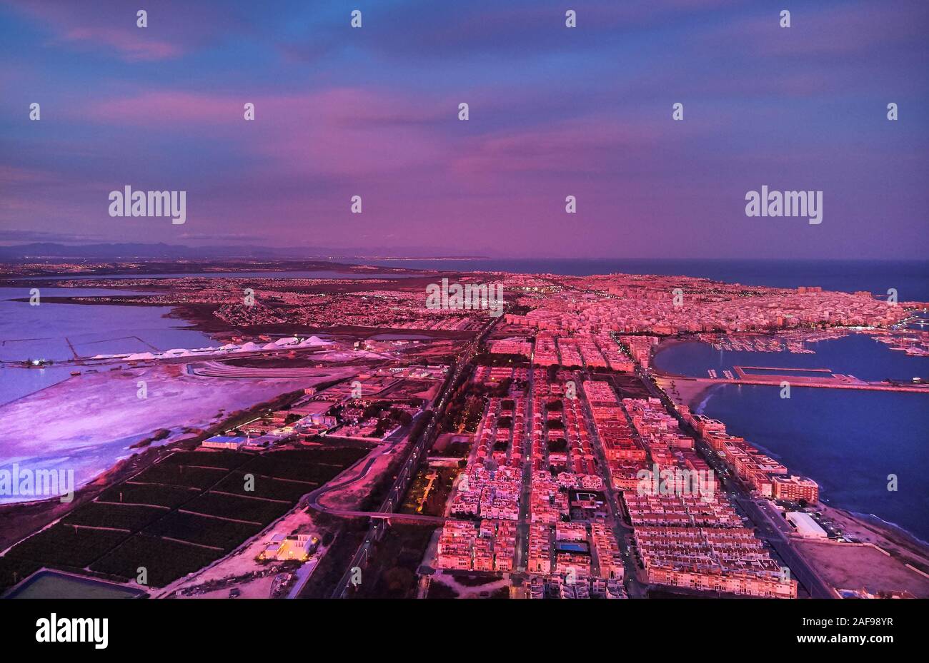 Photographie Aérienne au coucher du soleil pittoresque station balnéaire espagnole Torrevieja soir pourpre violet ciel nuageux. Salt Lake et la Méditerranée, le paysage urbain Banque D'Images