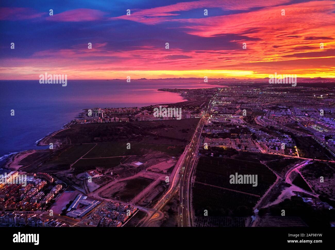 Pittoresque lumineux coucher de soleil sur la ville de Torrevieja touristique espagnol. Les couleurs éclatantes de l'horizon rougeoyant au coucher du soleil sur la mer Méditerranée, la photographie aérienne. C Banque D'Images
