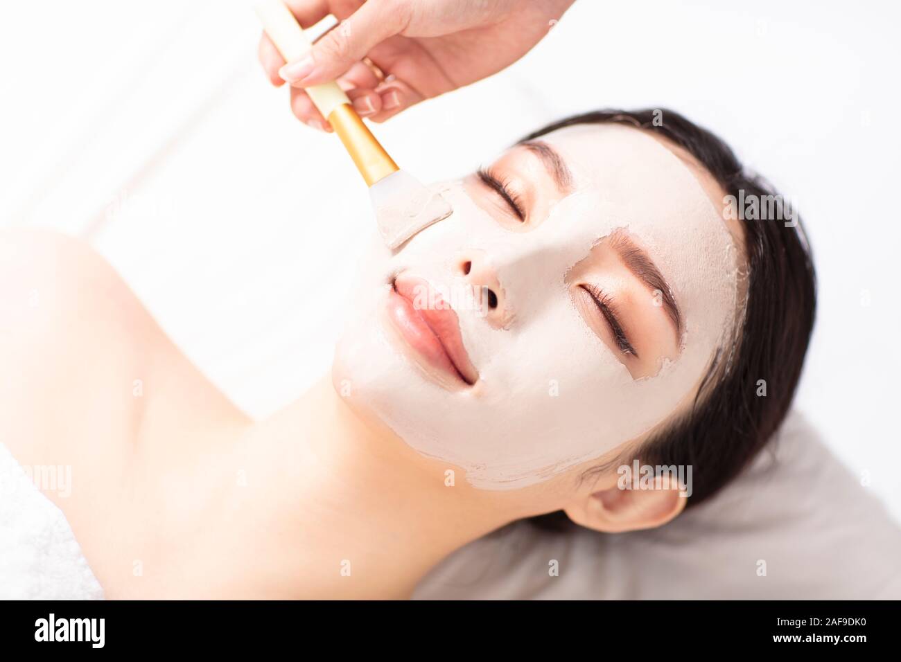 Jeune femme avec masque sur le visage en spa salon de beauté Banque D'Images