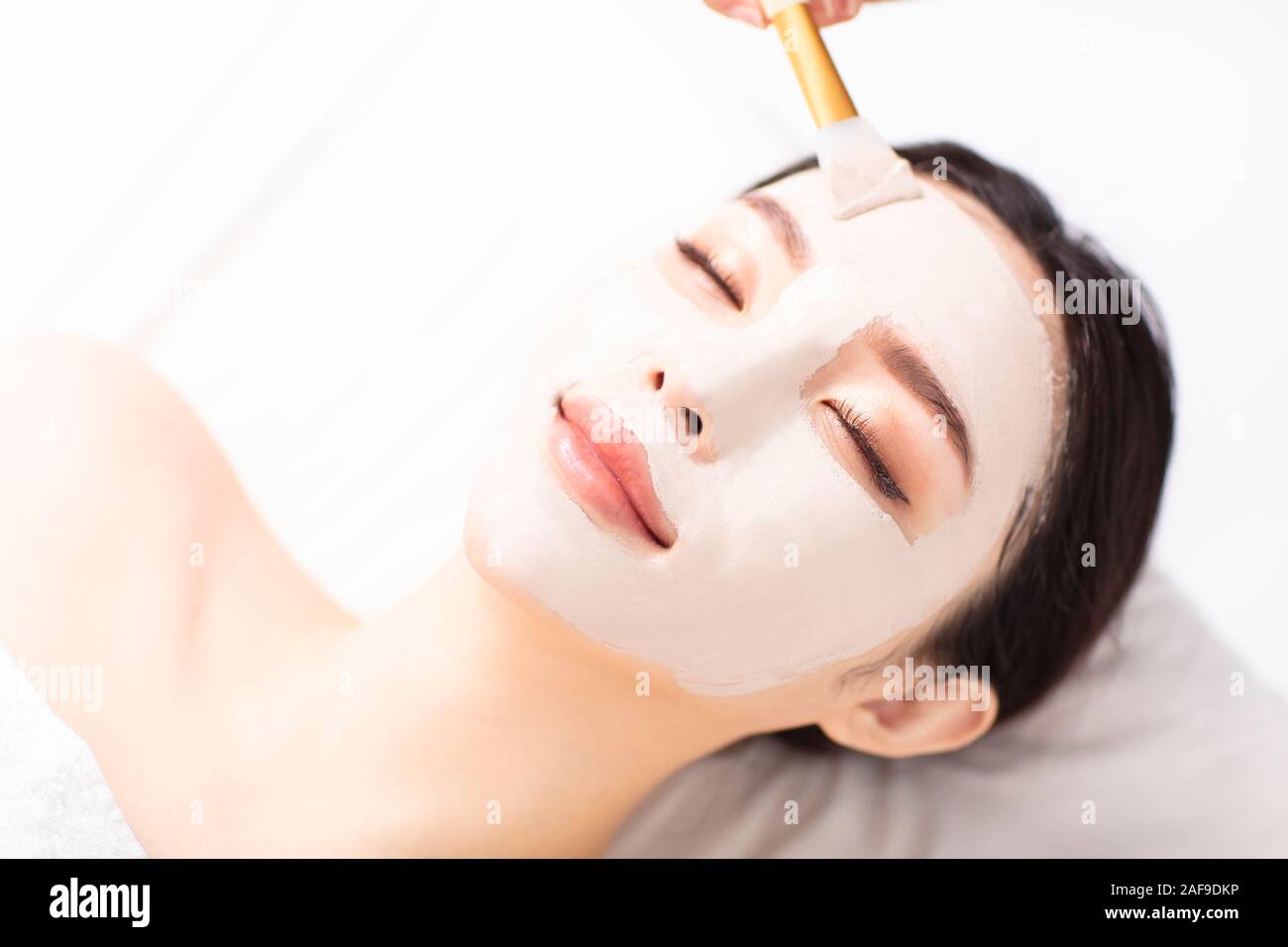 Jeune femme avec masque sur le visage en spa salon de beauté Banque D'Images