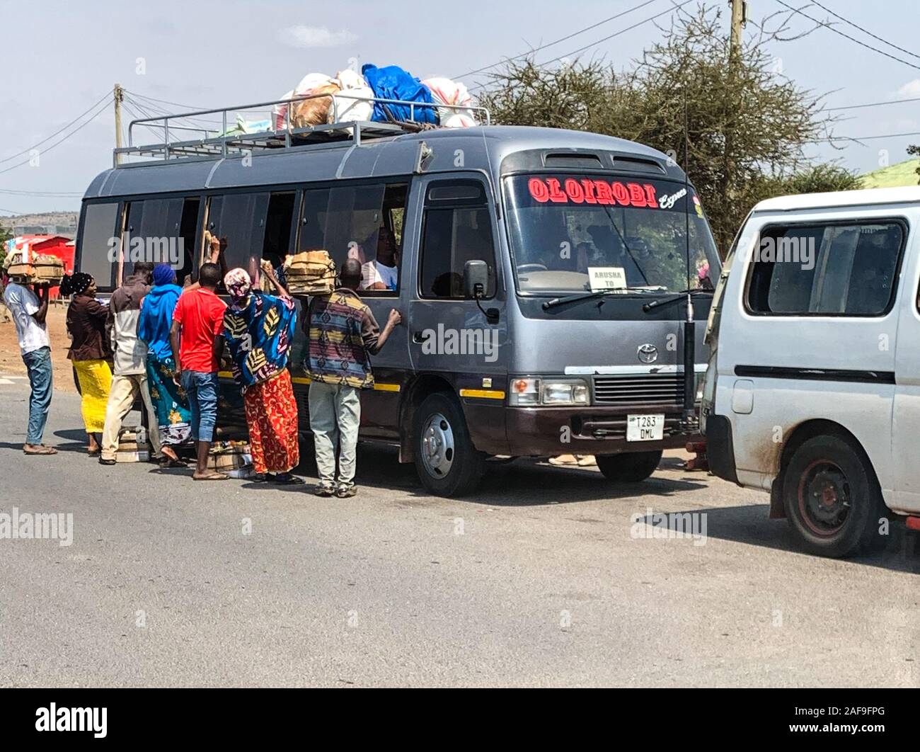 La Tanzanie. Marchands vendant de la nourriture aux passagers sur longue distance bus can. Banque D'Images