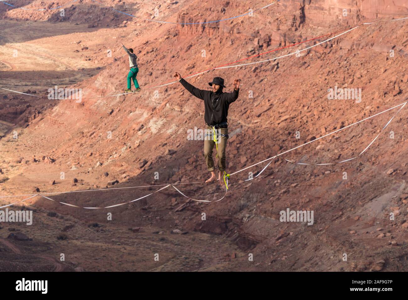 Deux hommes slackline ou highlining des centaines de pieds au-dessus du Canyon de minéraux près de Moab, en Utah pendant un rassemblement highline. Banque D'Images