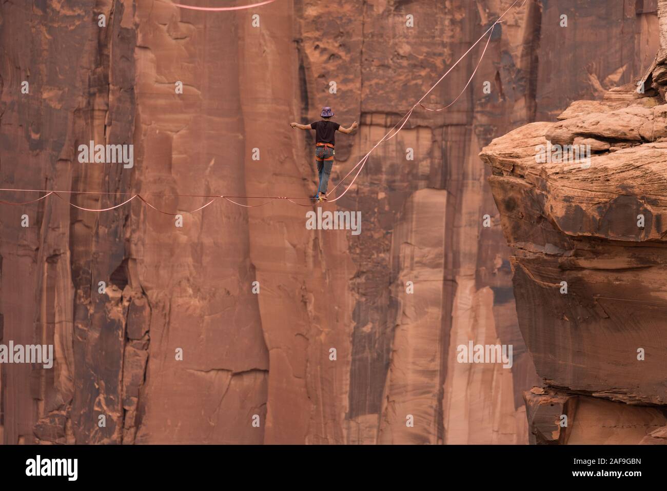 Un jeune homme slackline ou highlining des centaines de pieds au-dessus du Canyon de minéraux près de Moab, en Utah pendant un rassemblement highline. Banque D'Images