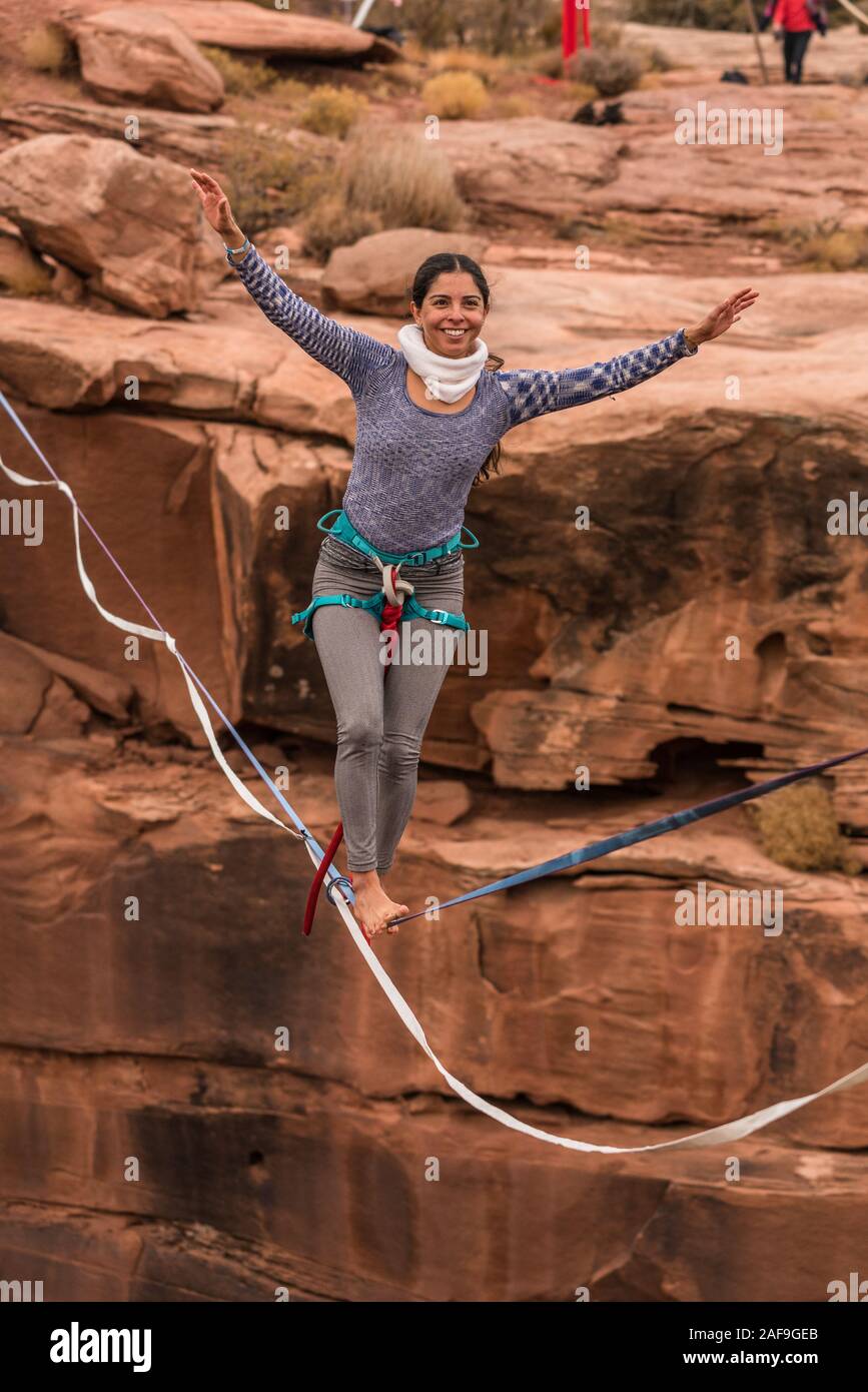 Une jeune femme slackline ou highlining des centaines de pieds au-dessus du Canyon de minéraux près de Moab, en Utah pendant un rassemblement highline. Banque D'Images