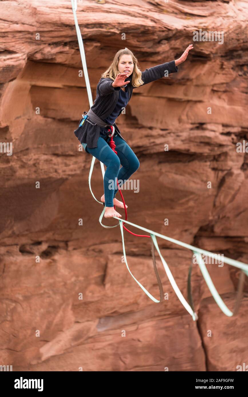 Une jeune femme se bat pour maintenir son équilibre tout en slackline ou highlining des centaines de pieds au-dessus du Canyon de minéraux près de Moab, en Utah pendant un highlin Banque D'Images