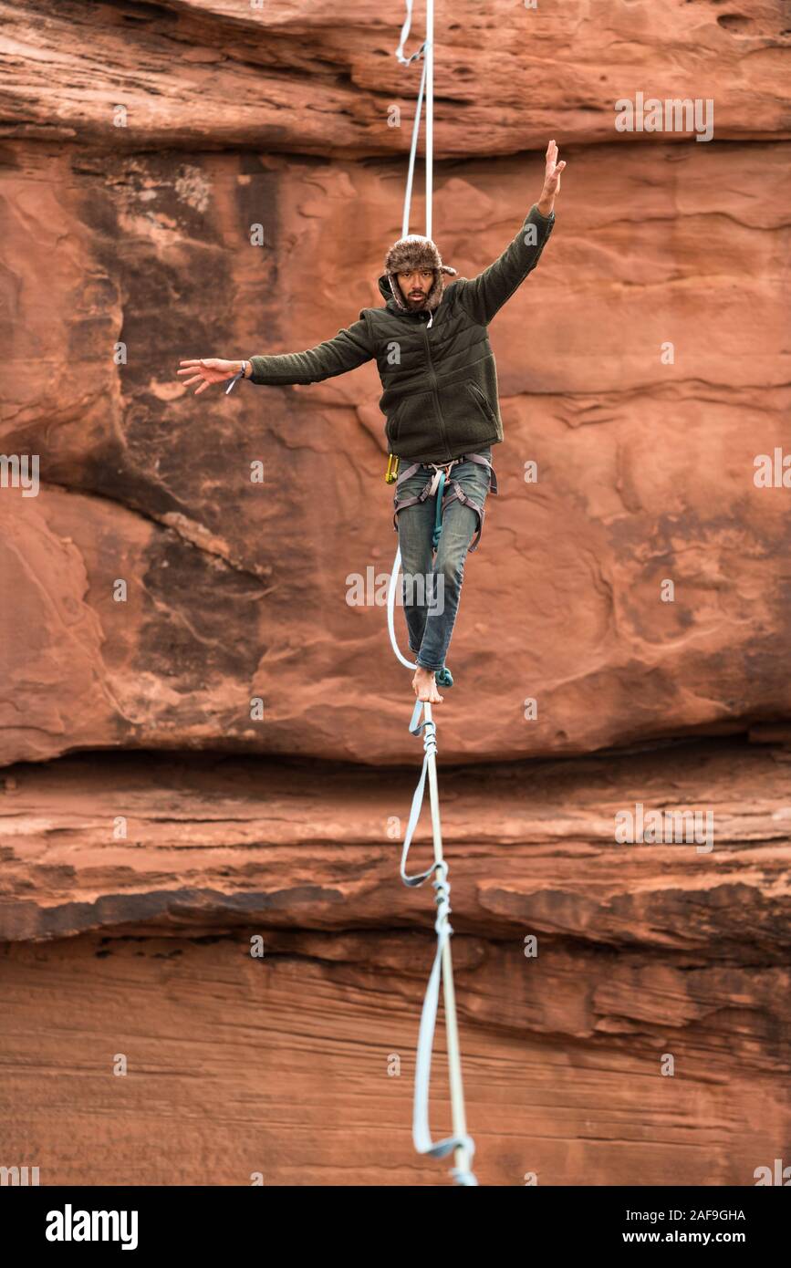 Un jeune homme slackline ou highlining des centaines de pieds au-dessus du Canyon de minéraux près de Moab, en Utah pendant un rassemblement highline. Banque D'Images