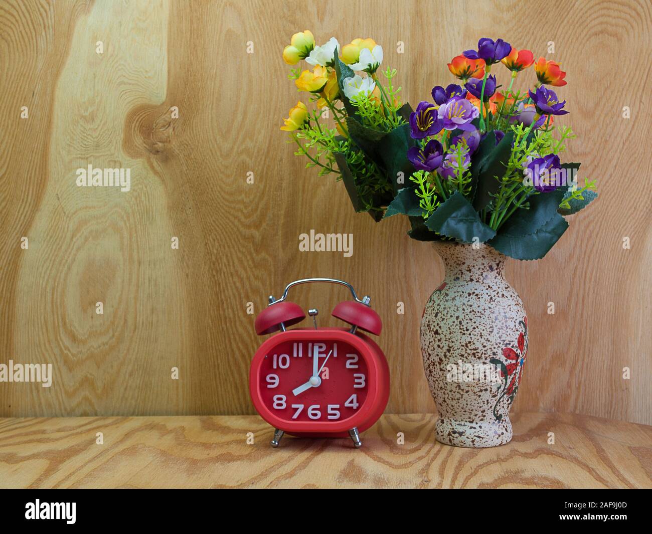 Réveil , de belles fleurs dans vase , placé sur un plancher en bois. Banque D'Images