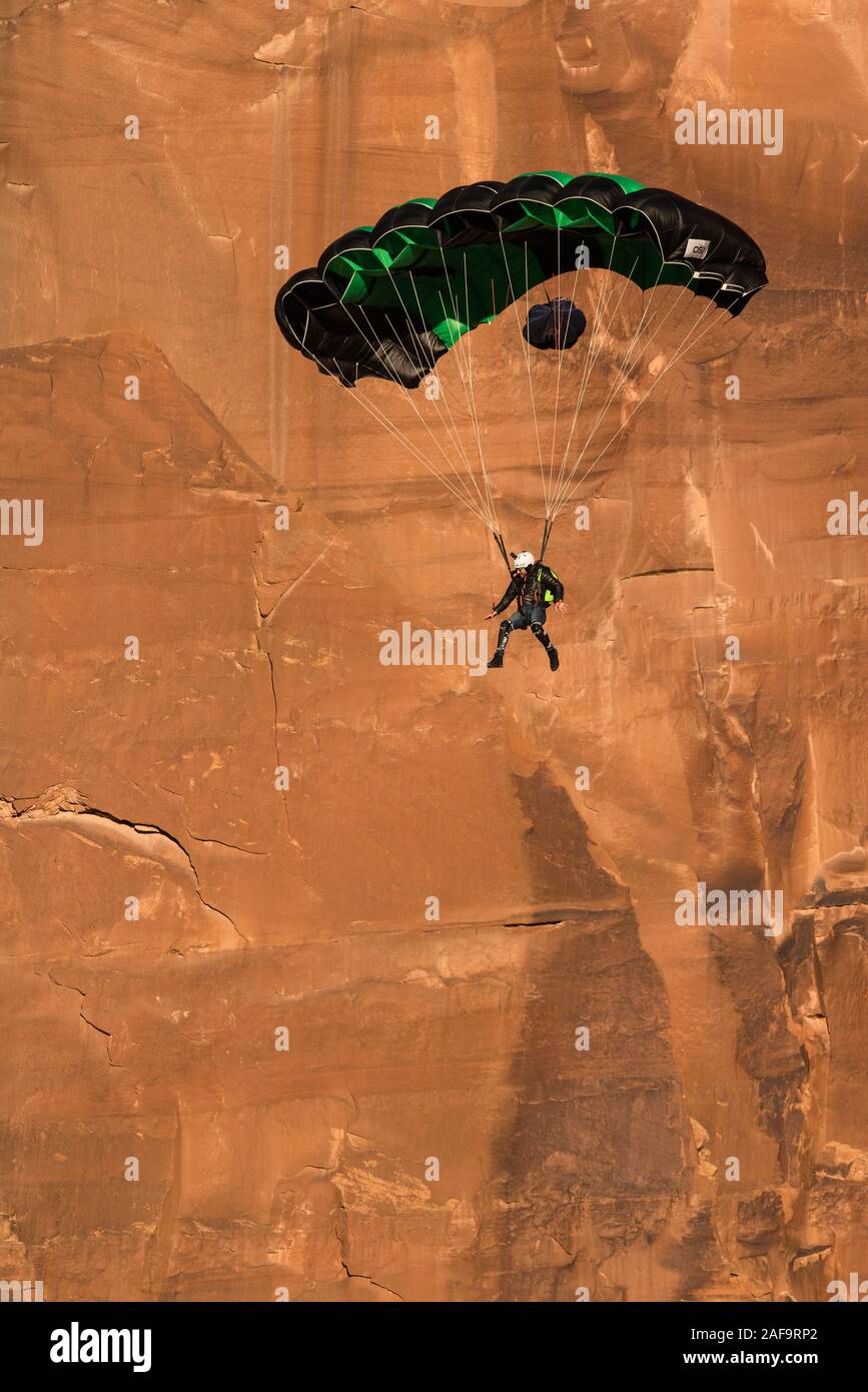Un cavalier BASE descend dans son parachute au large de la face verticale de 400 pieds de la pierre tombale dans Kane Springs Canyon près de Moab, Utah. Banque D'Images