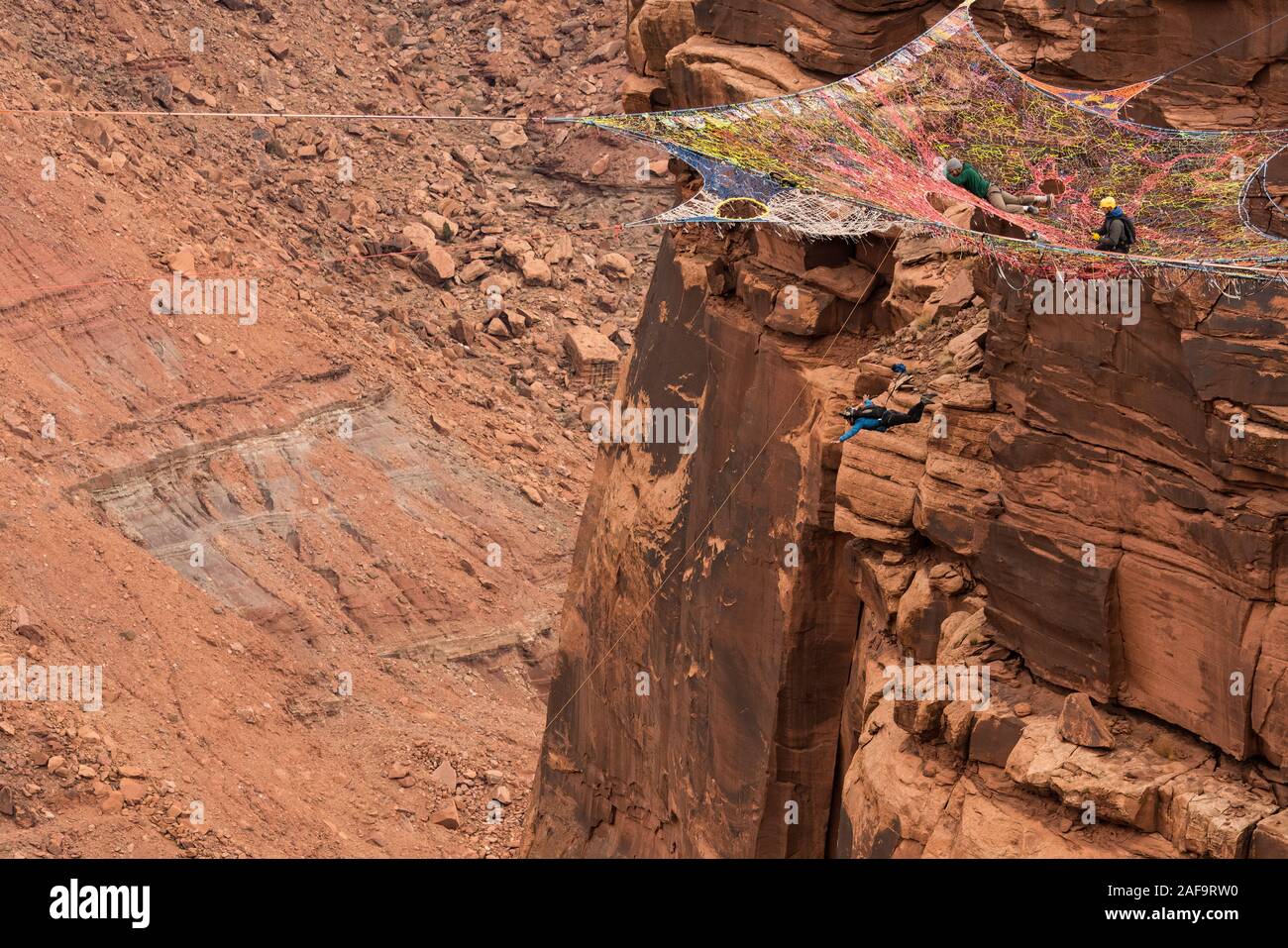 Une femelle cavalier BASE de sauts le ravitailleur Espace Net suspendu de la falaise verticale de 950 pieds au-dessus de la vallée à minéral Canyon près de Moa Banque D'Images