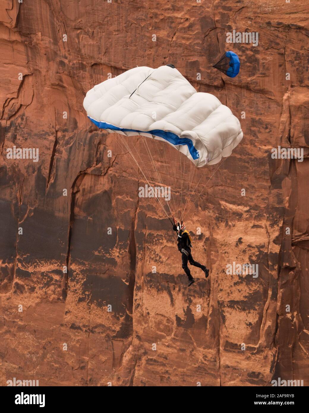 Un cavalier BASE descend dans son parachute à partir de la falaise verticale de 950 pieds au-dessus de la vallée à près de Canyon minéral Moab, Utah. Banque D'Images