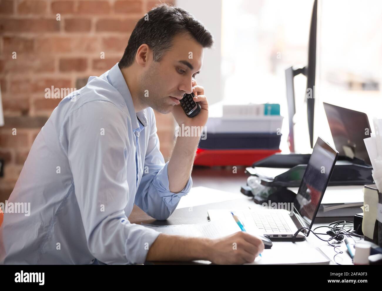 Serious businessman talking on phone avoir journée de travail Banque D'Images