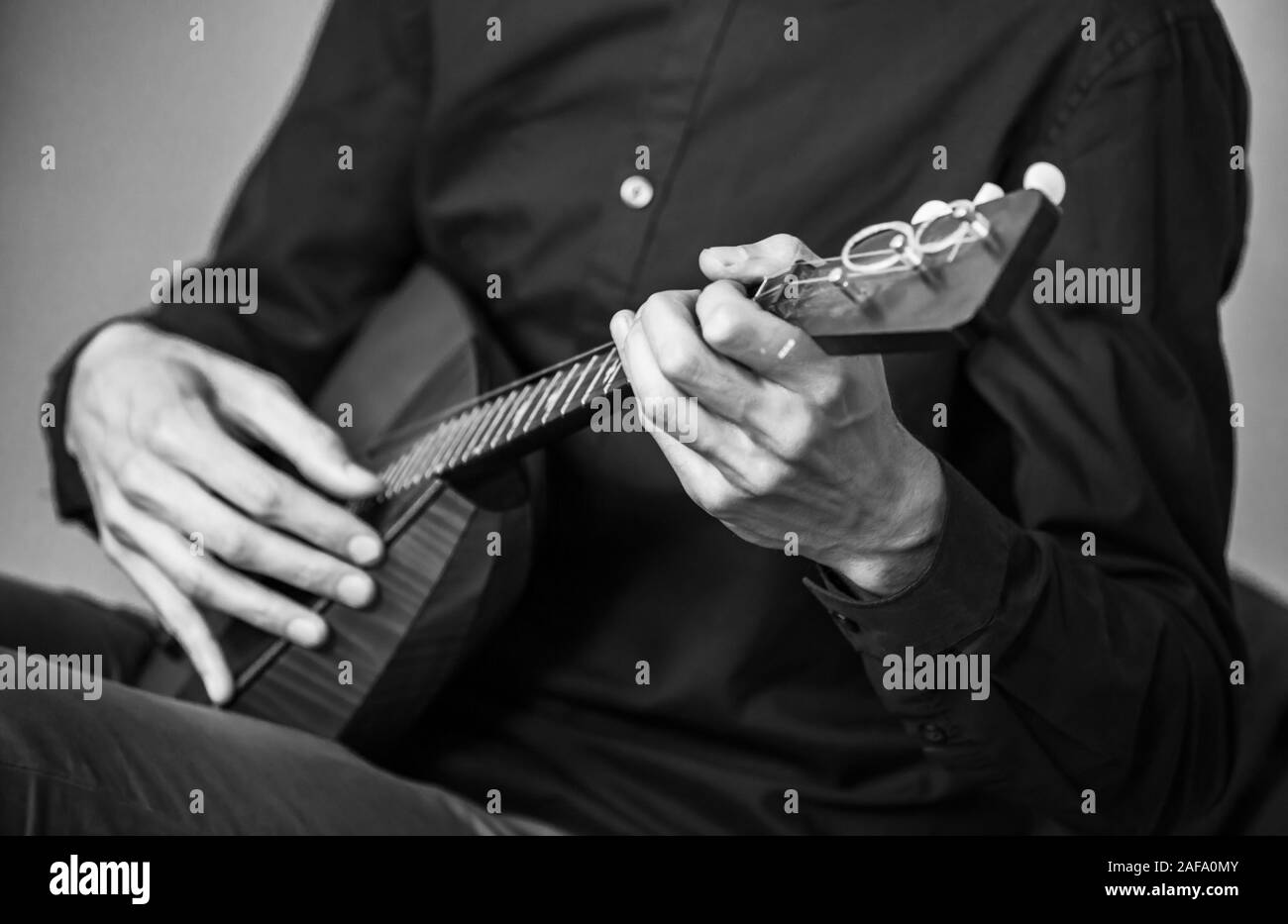 Mains d'un homme jouant de la balalaïka, close-up photo avec mise au point sélective et l'effet de flou. Retro photo noir et blanc stylisé Banque D'Images