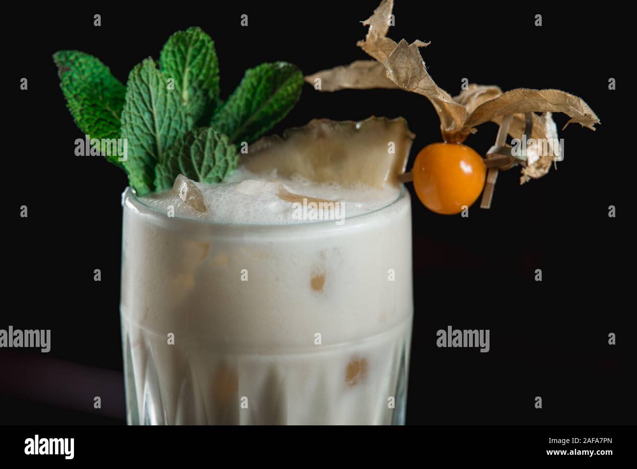 Cocktail Pina Colada tropical exemplaire. boisson mélangée avec du rhum, ananas et noix de coco. Décorées avec un morceau d'ananas et menthe congé. Black Banque D'Images