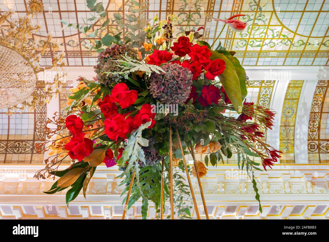 Bouquet de luxe. Bouquet de fleurs sur fond d'intérieur de luxe. Décoration florale originale en forme de bouquet de fleurs rouge jaune et vert sur fond de couleurs pastel. Superbe lustre au plafond Banque D'Images