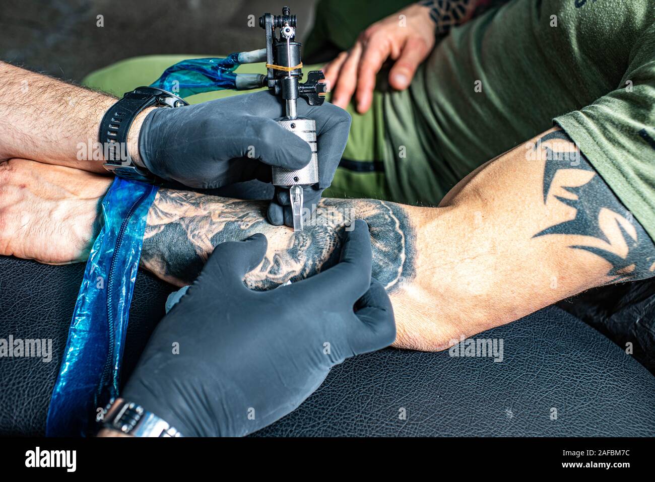 Tatoueur en gants noirs attire de nouveaux tatouage noir avec machine à  tatouer sur son bras masculins. Salon de tatouage Photo Stock - Alamy