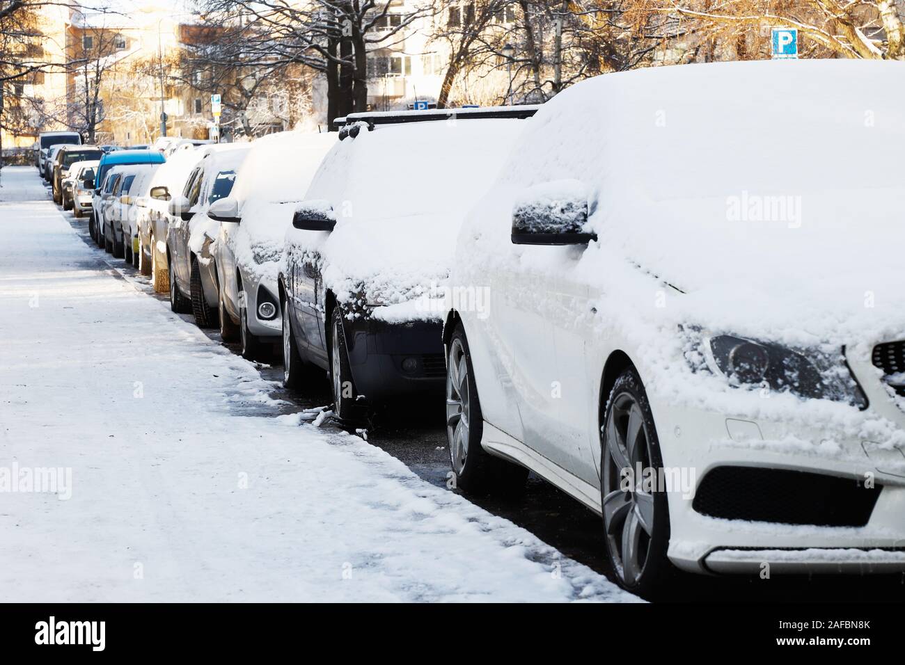 La neige a couvert de voitures stationnées dans un quartier résidentiel. Banque D'Images
