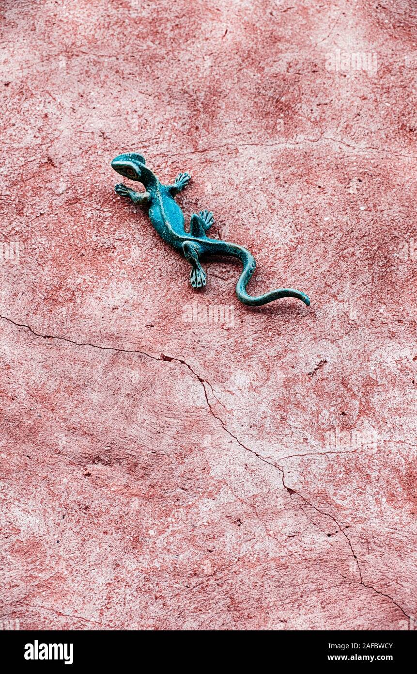 Un gecko vert décoration murale est placée sur un mur en stuc fissuré dans la ville de Roussilon en France. Banque D'Images