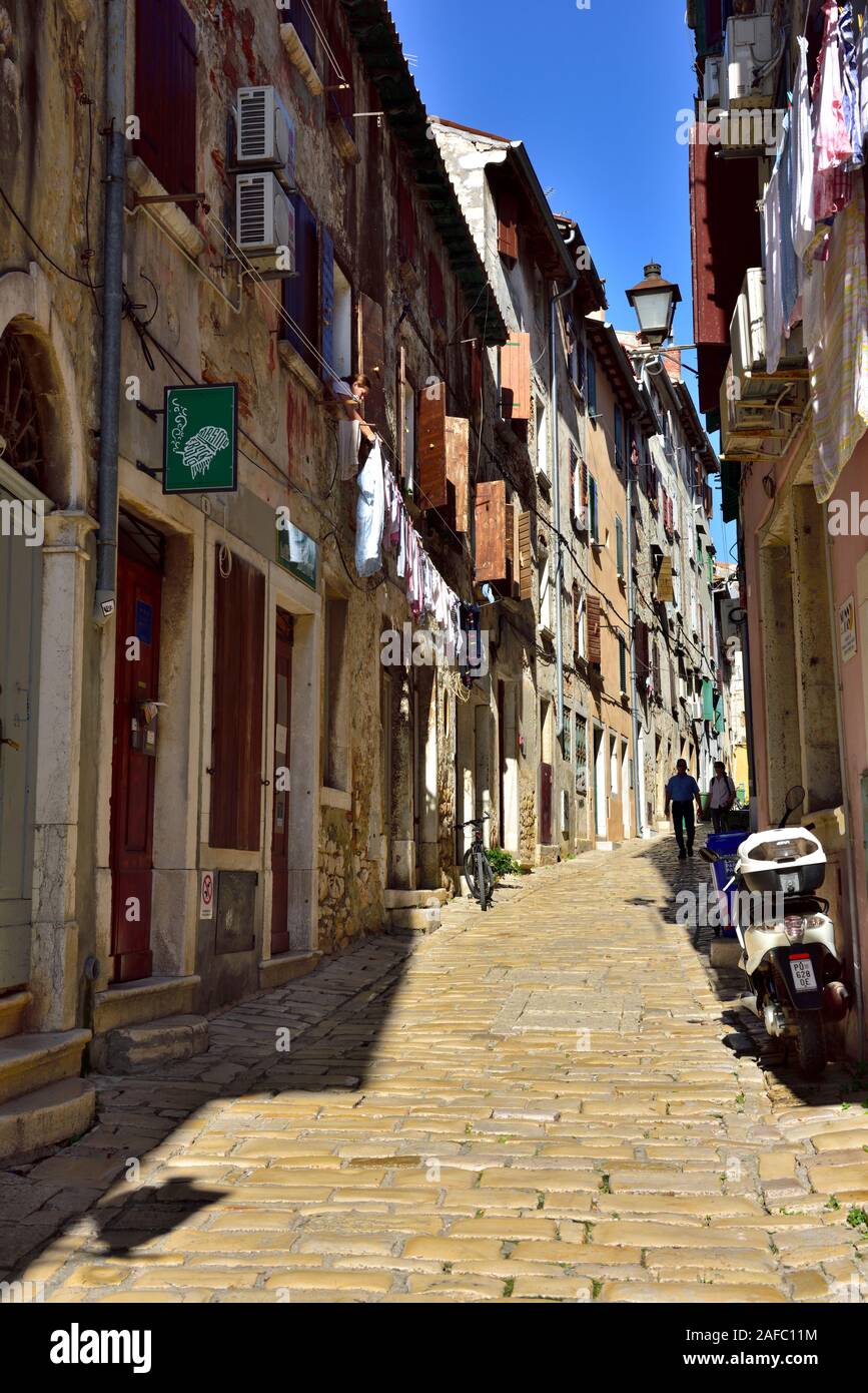 Petite rue pavée avec ancien bâtiment de chaque côté, blanchisserie hanging out, volets sur windows, Rovinj, Croatie Banque D'Images