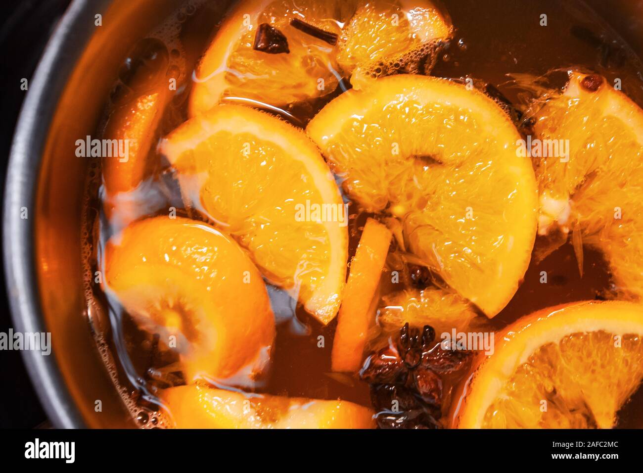 La préparation de boissons vin chaud avec des oranges et des épices. Les boissons de Noël faire bouillir dans le moule en métal. Glintwine de vin rose avec des agrumes, de girofle Banque D'Images