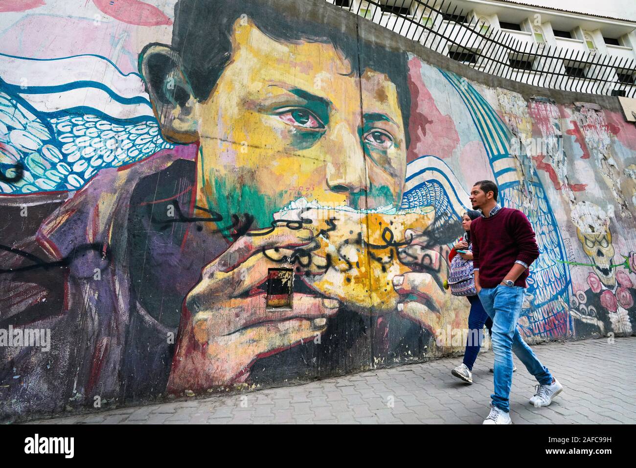 Homme marche devant une fresque révolutionnaire sur un mur des martyrs près de la place Tahrir au Caire, en Égypte. La toile commémore la mort des manifestants de la place Tahrir pendant la révolution de 2013 Banque D'Images