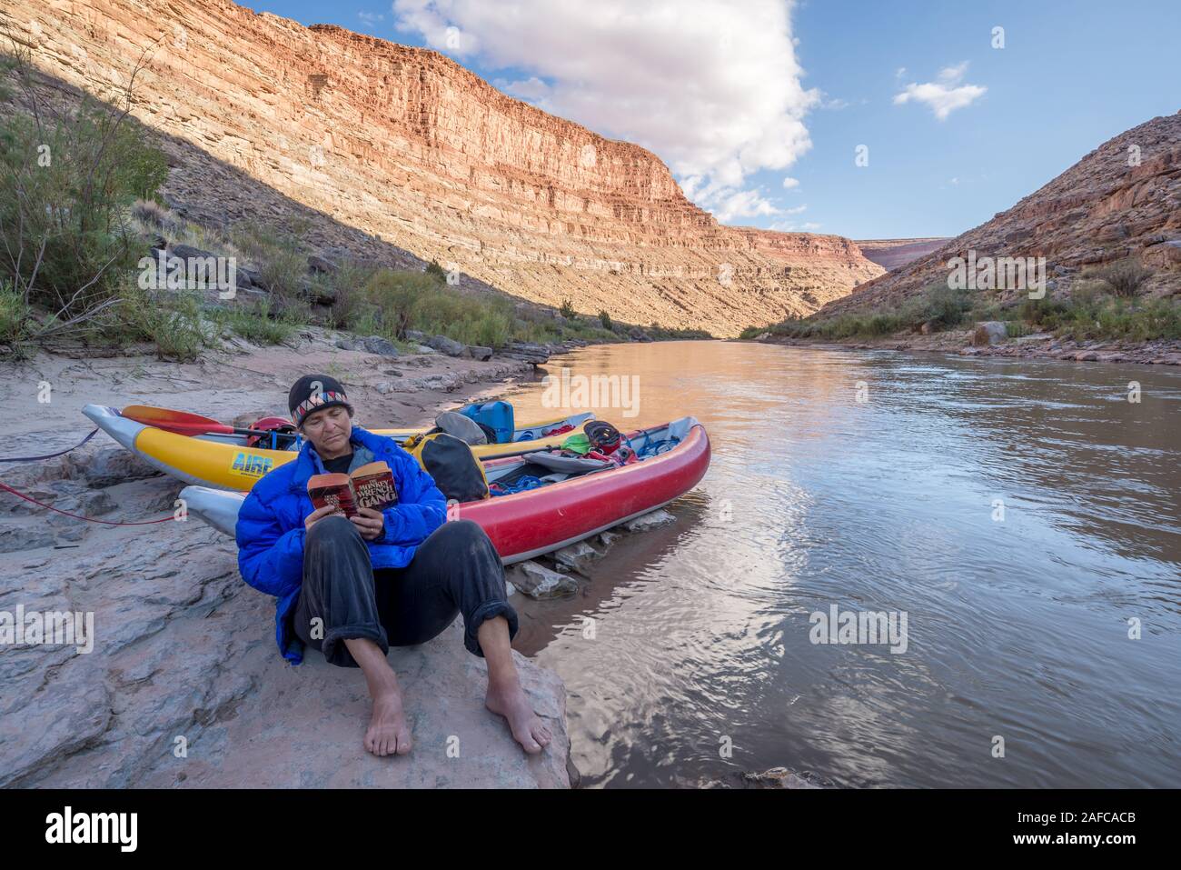 Femme lisant un livre dans un camping sur la Rivière San Juan, dans l'Utah. Banque D'Images