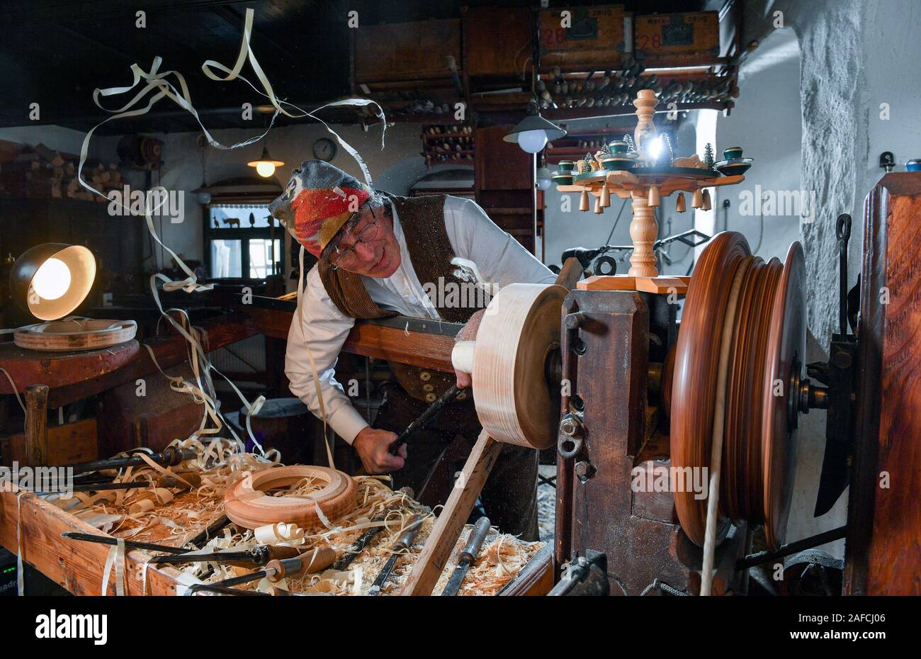 11 décembre 2019, Saxe, Seiffen : jouet en bois bouilloire et le pneu tourneur Christian Werner travaille sur le tour dans son atelier à Seiffen. Les outils spéciaux sont utilisés pour activer le profil d'une figure dans le bois mouillé. Seulement après avoir partagé la silhouette de la figure de révéler lui-même. Les blancs sont plus tard, sculptés et peints ou collés. La technologie dans le petit atelier avec ses six employés est toujours le même qu'il y a 200 ans, lorsque la rotation de pneus dans les monts Métallifères a commencé. L'embarcation en Seiffen est aujourd'hui unique au monde et se pratique seulement par une poignée de woode Banque D'Images