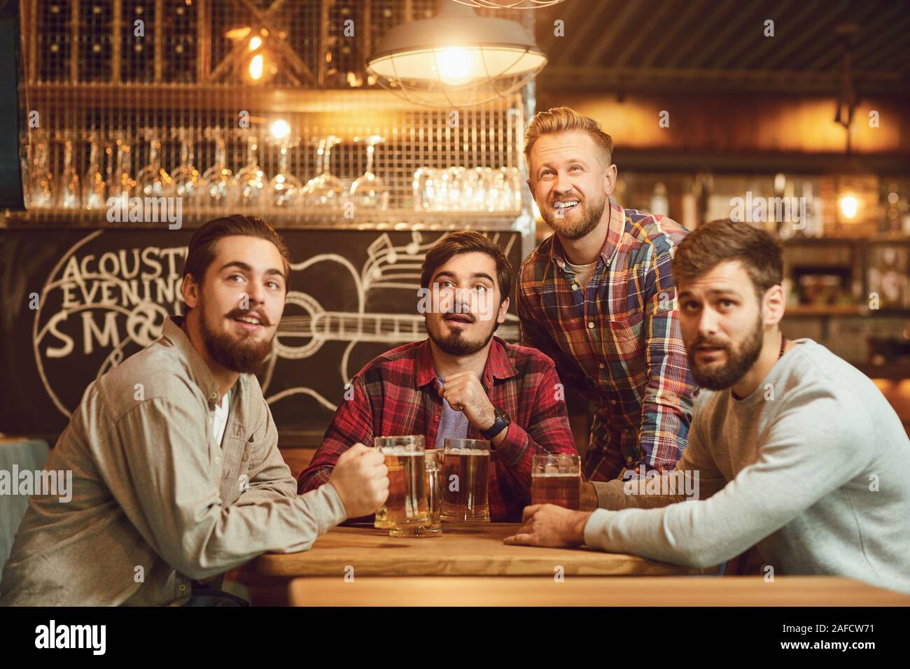 Un groupe de gars à regarder du sport à la télévision dans un pub et bar. Banque D'Images