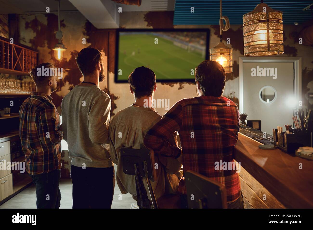 Un groupe de personnes regardant la télévision football dans un bar sportif. Banque D'Images