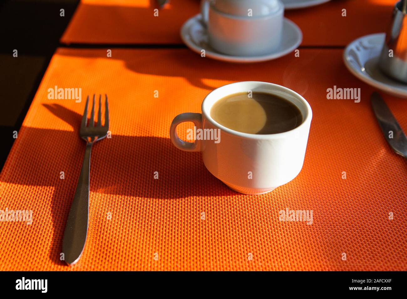 Profondeur de champ (selective focus) image avec une tasse de café chaud et d'une fourchette sur une table pendant le petit déjeuner tôt le matin. Banque D'Images