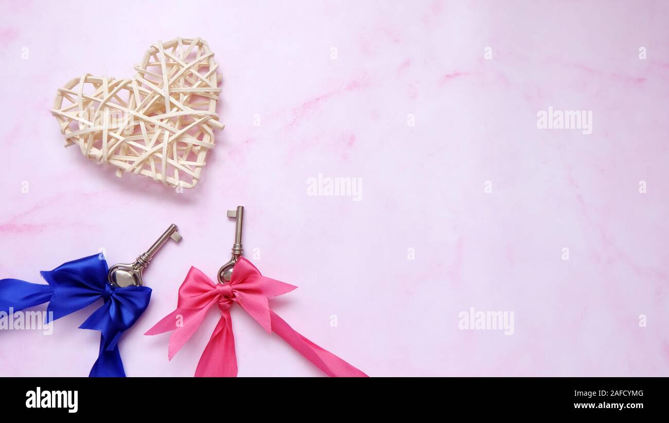 Une paire de clés correspondantes avec ruban rose et bleu, avec un cœur au dessus, et copier l'espace sur la droite. Banque D'Images