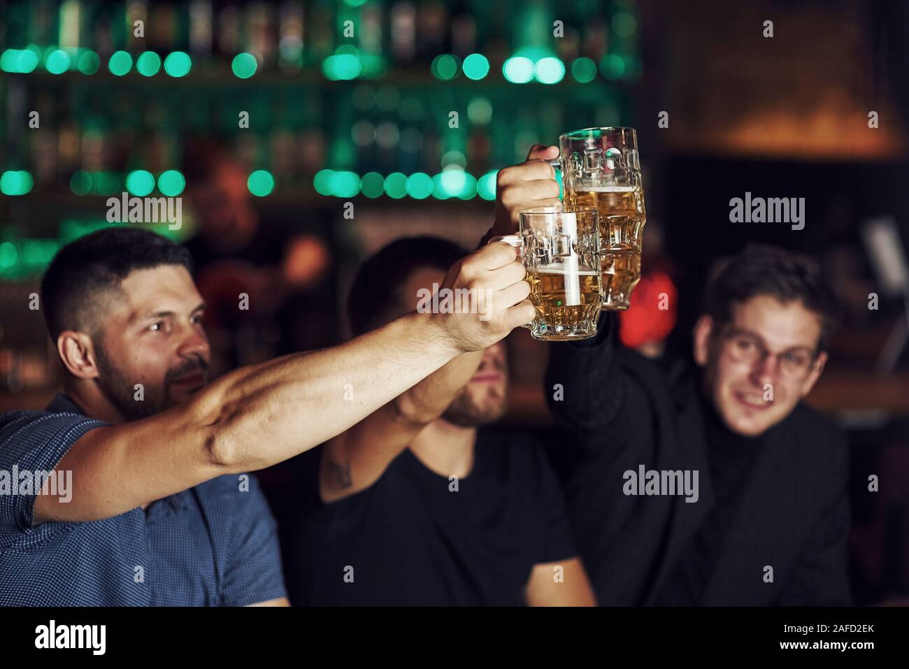 Lunettes de cognement. Trois sports fans dans un bar à regarder le football. Avec la bière en mains Banque D'Images