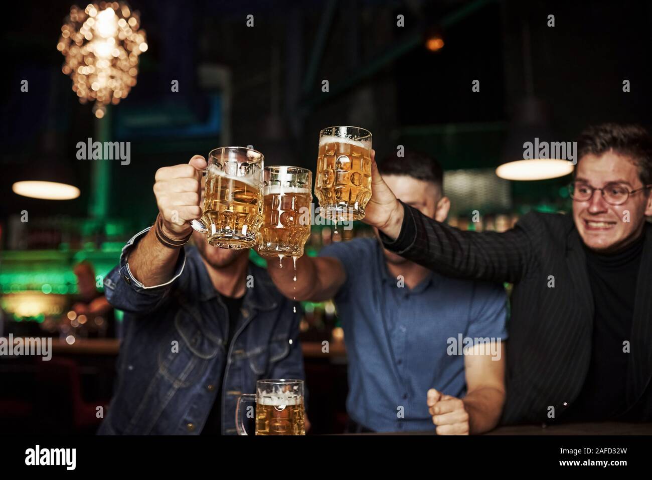 Lunettes de cognement. Trois sports fans dans un bar à regarder le football. Avec la bière en mains Banque D'Images