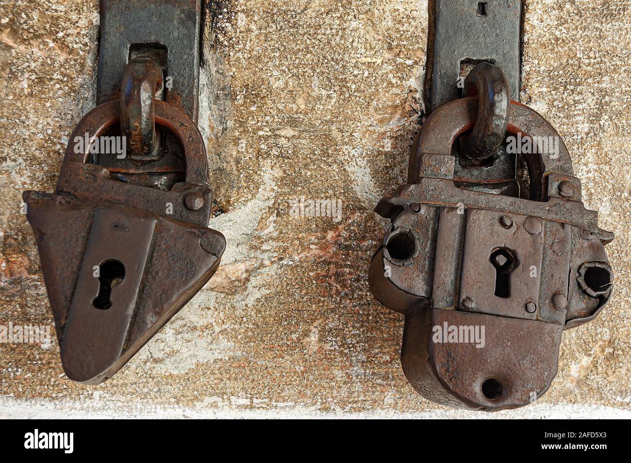 Close-up de deux anciennes cadenas rouillé avec poignée avec un mur de pierre sur l'arrière-plan Banque D'Images