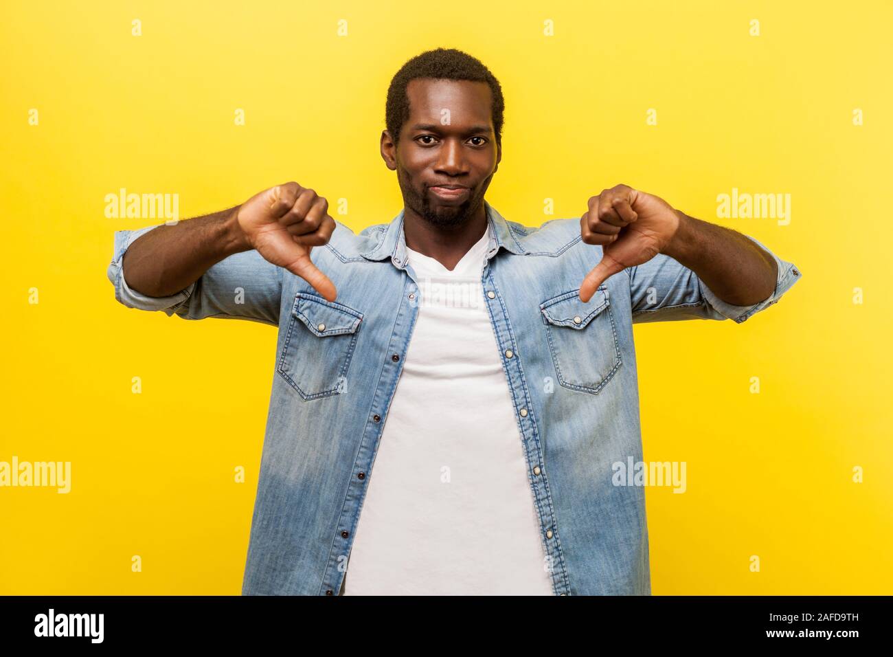 N'aiment pas, la rétroaction négative. Portrait d'homme en colère mécontent en denim chemise décontractée showing Thumbs down geste, signe de désapprobation, exprimant le rejet Banque D'Images