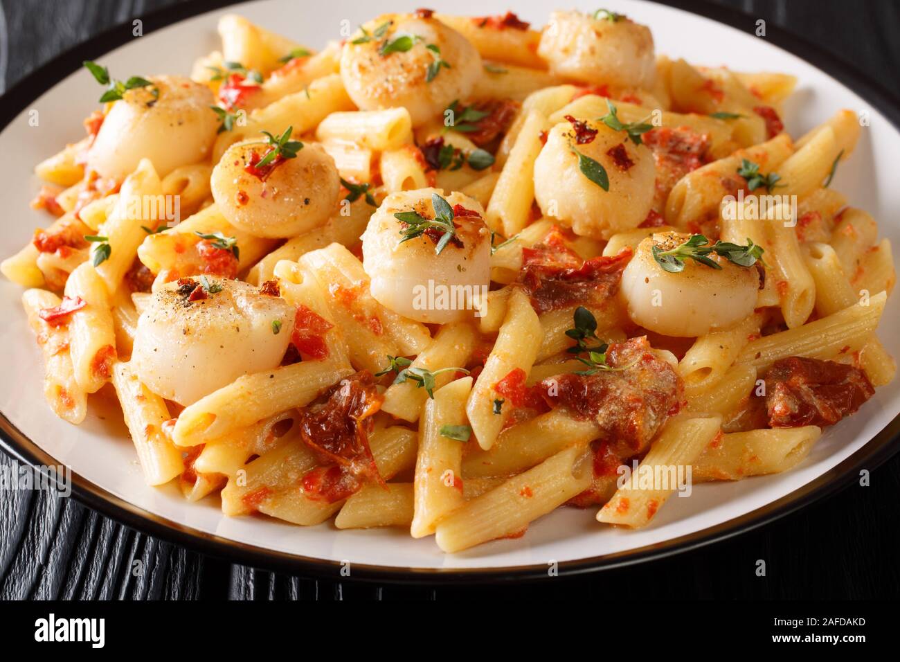 La cuisson des pâtes penne avec poulet, tomates séchées et thym close-up dans une assiette sur la table horizontale. Banque D'Images