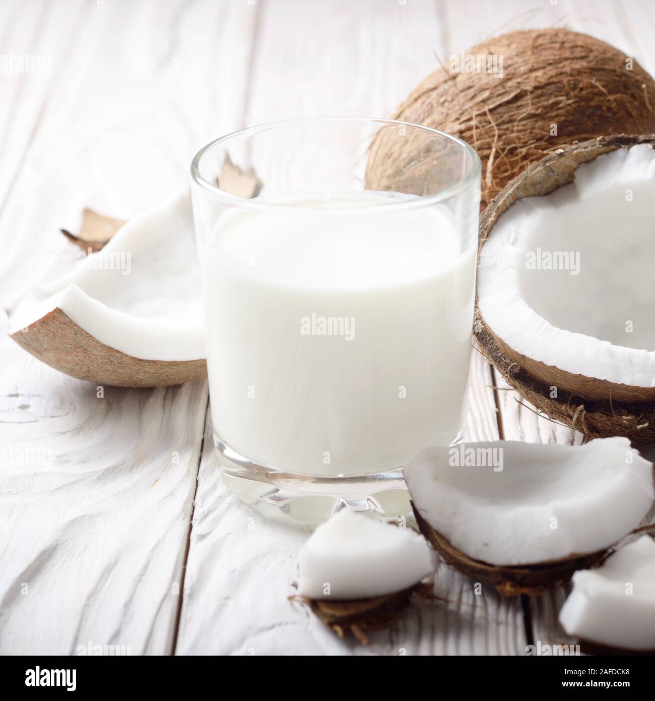 Boire un verre de lait ou de yogourt sur bleu serviette sur une table en bois blanc à la noix de coco de côté Banque D'Images