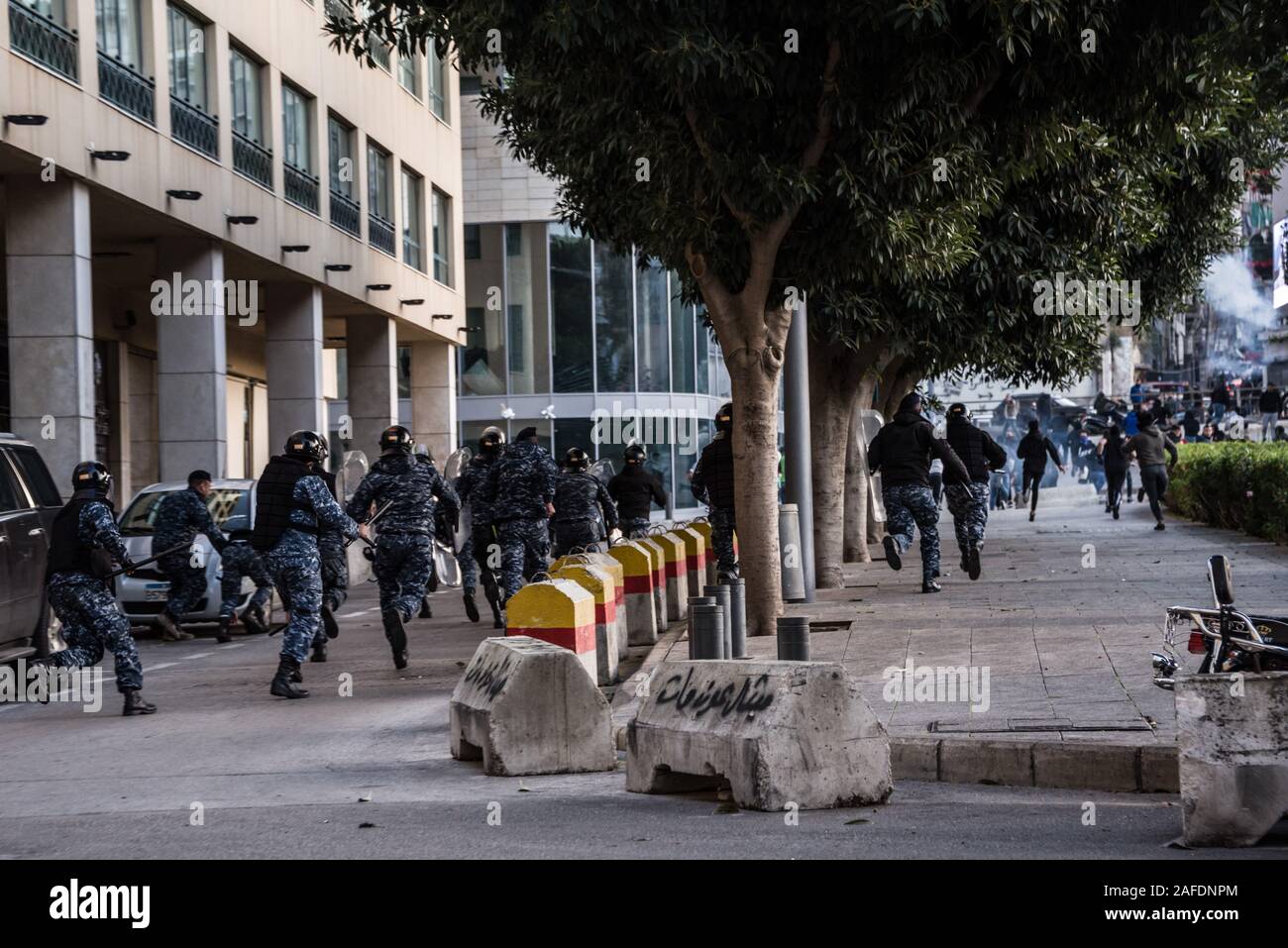 Beyrouth, Liban. 14 Décembre, 2019. Les forces de sécurité de chasser les gens agés qui protestaient contre une révolte contre le gouvernement libanais à travers les rues sur la 59e journée de protestation. Du quartier chiite de Bachoura, près du centre-ville de Beyrouth, des contre-manifestants ont attaqué la police et le personnel de l'armée avec des pierres et des feux d'artifice le samedi soir. La police a répondu par des gaz lacrymogènes lors d'une bataille de plusieurs heures. Credit : Elizabeth Fitt/Alamy Live News Banque D'Images