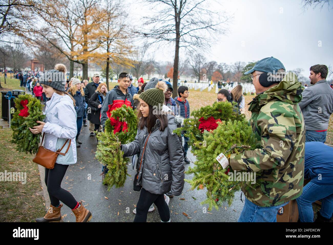Arlington, États-Unis d'Amérique. 14 Décembre, 2019. Les bénévoles portent des couronnes pour placer sur les tombes de membres de l'ensemble des couronnes au cours de la 28e Journée de l'Amérique au cimetière national d'Arlington, le 14 décembre 2019 à Arlington, en Virginie. Plus de 38 000 couronnes au lieu des bénévoles chaque tombe au cimetière national d'Arlington et autres sites autour de la nation. Credit : Elizabeth Fraser/DOD/Alamy Live News Banque D'Images