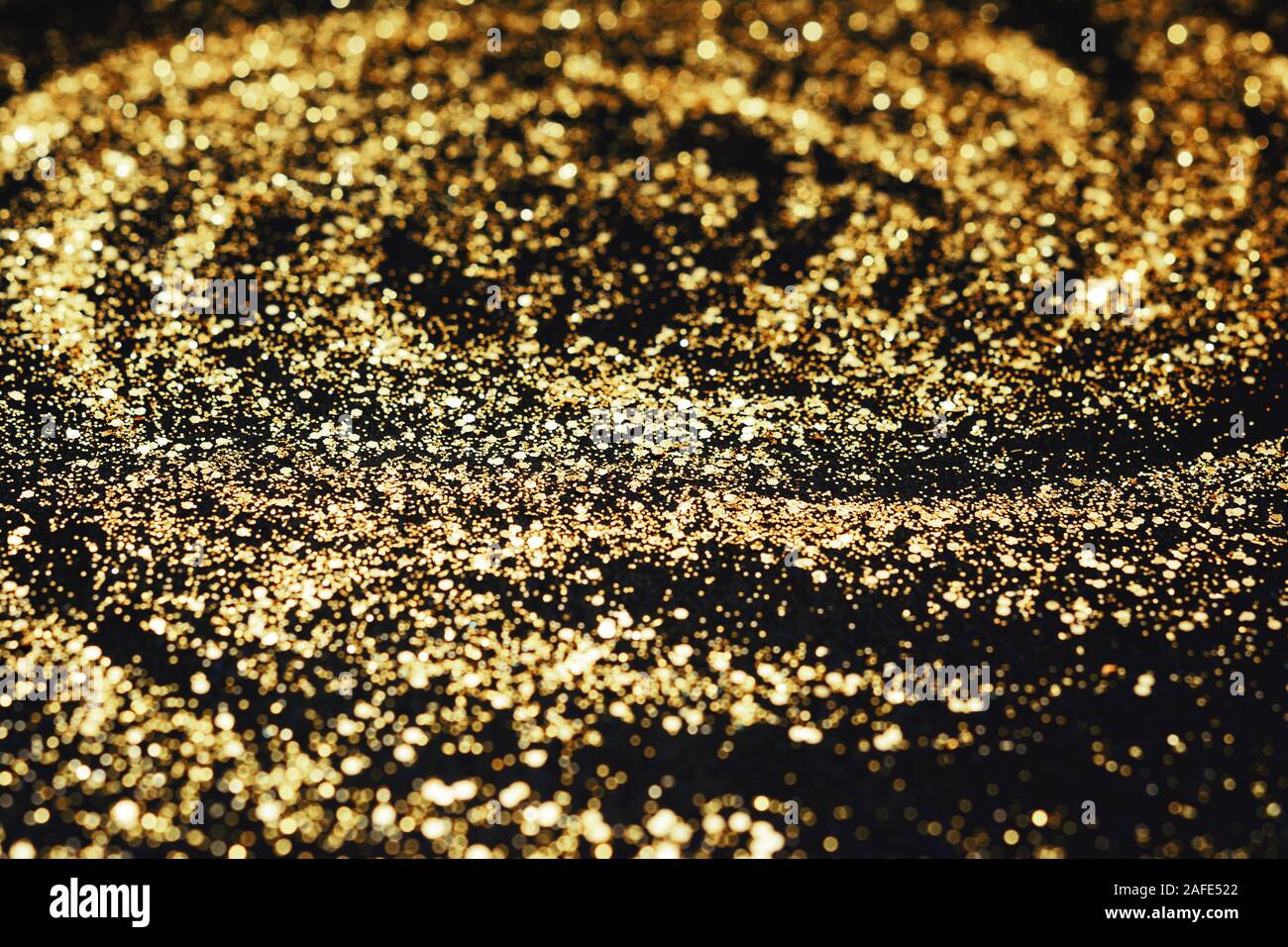 Paillettes d'or sur le fond noir, vue du dessus. Abstract pattern créé à la main, imitaion de tempête, selective focus Banque D'Images