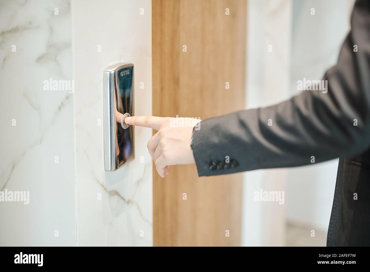 Main de businessman appuyant sur le bouton de l'élévateur en position debout à sa porte Banque D'Images