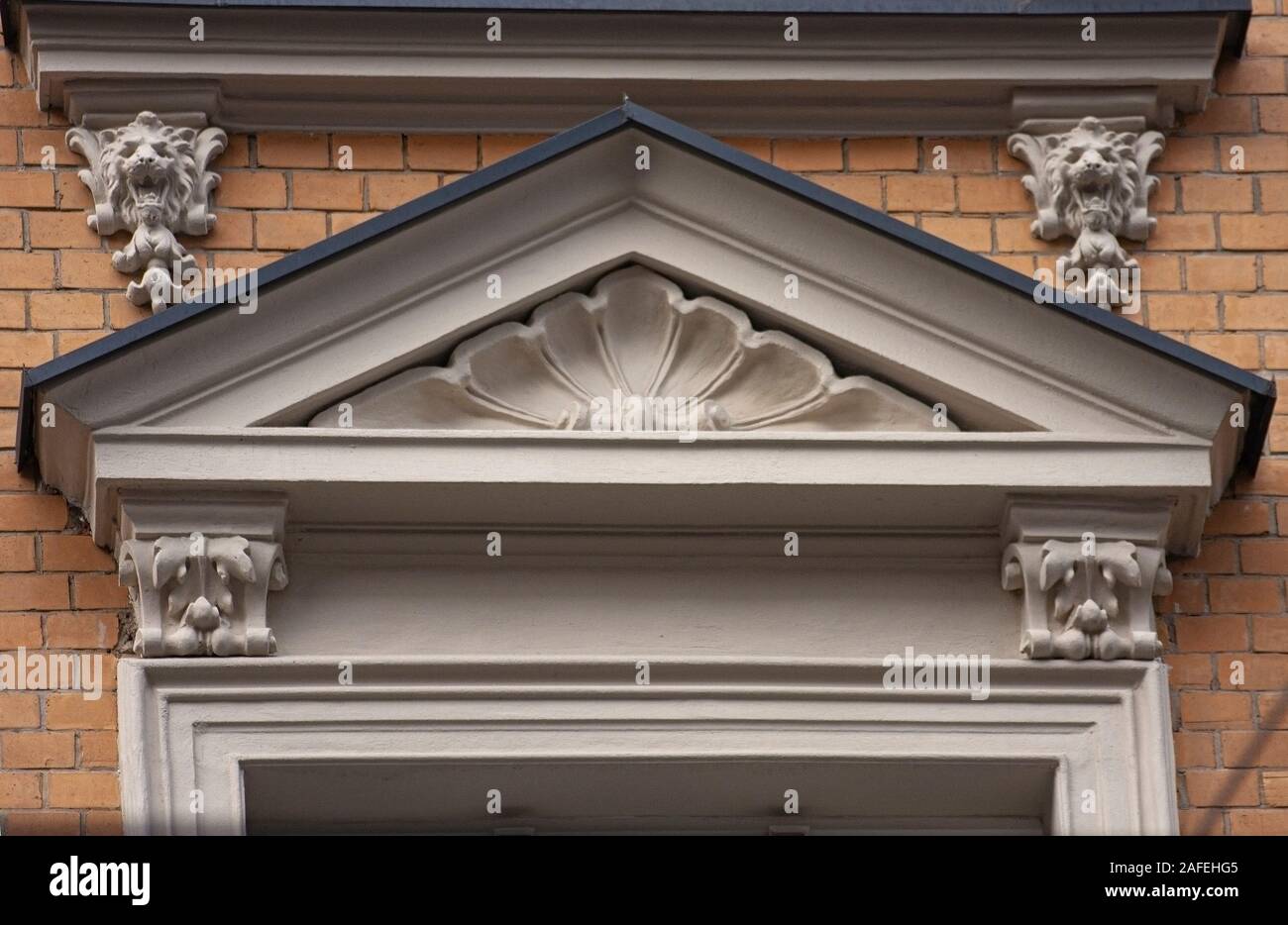 Immeuble éclectique arch shell portes de secours tête de lion en pierre ancienne ornement détail brique jaune Banque D'Images