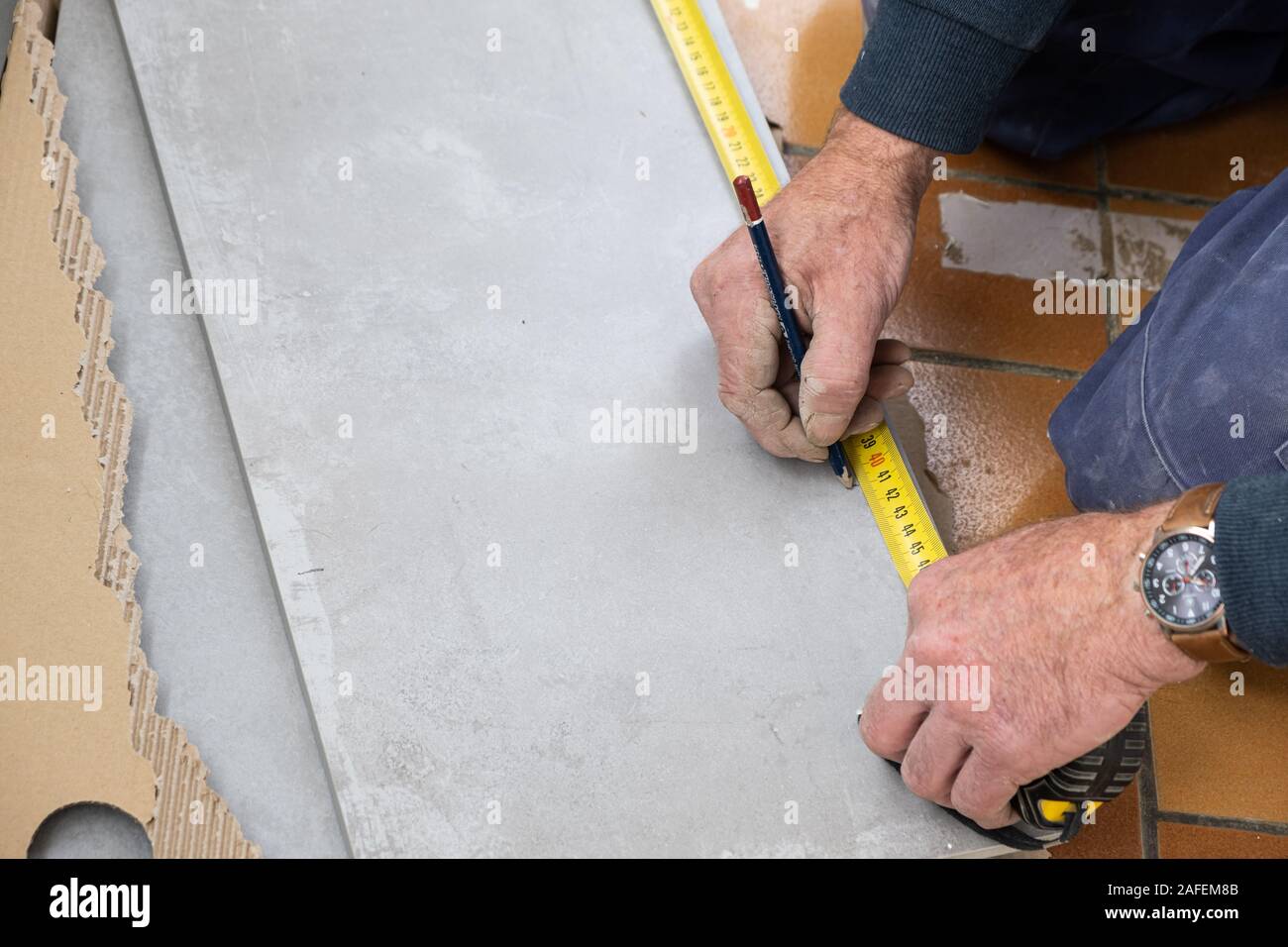 Le carreleur mesure les carreaux avant qu'elle coupe Banque D'Images