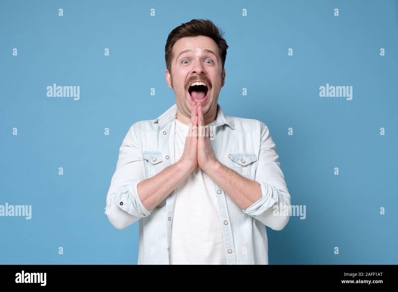 Jeune homme excité émotionnel s'exclamant en état de choc et d'incrédulité complète, gesticulant activement. Des émotions faciales positive, sentiment. Studio shot Banque D'Images