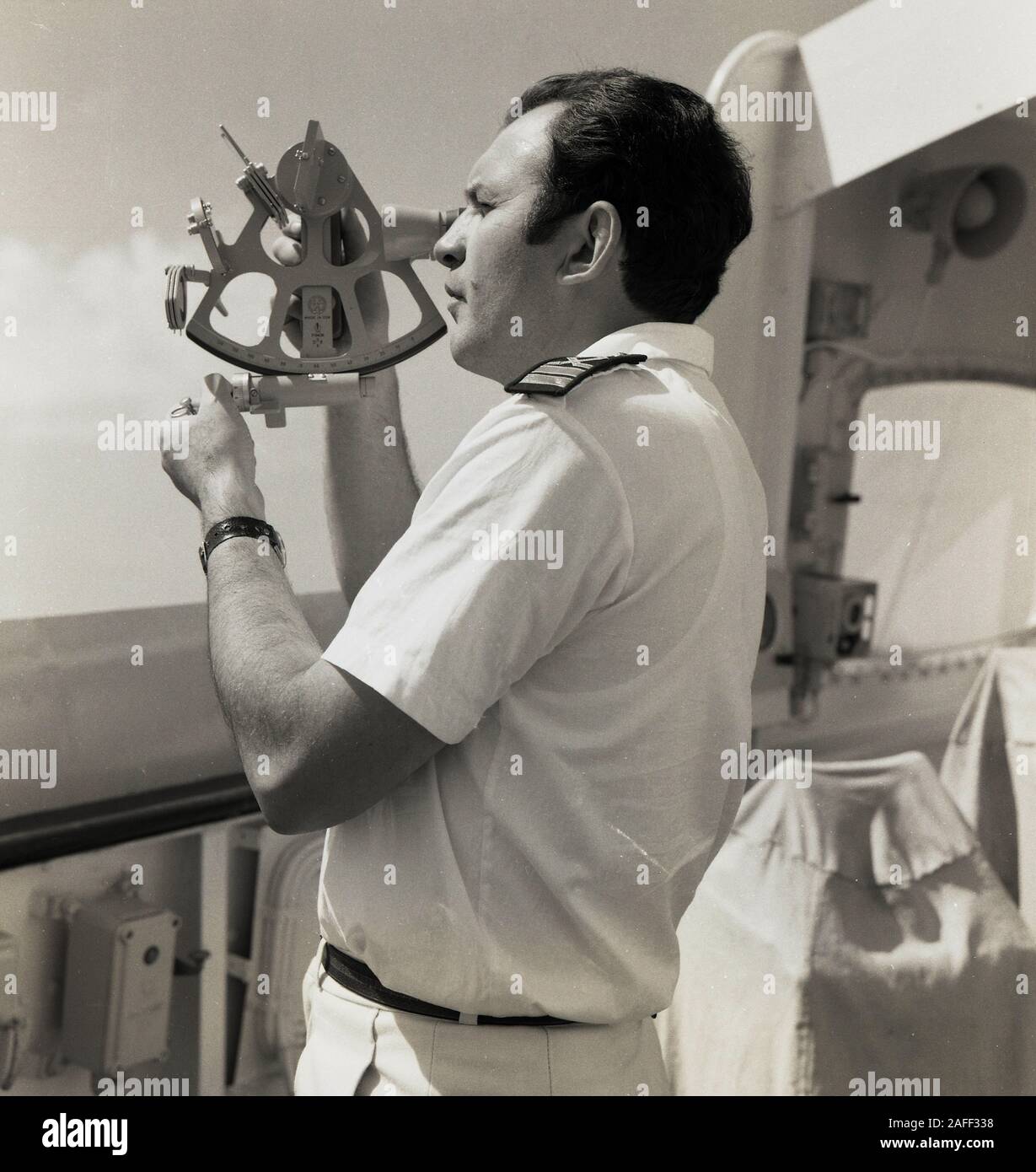 années 1960, historique, un navigateur en uniforme à l'extérieur sur le pont d'un bateau de croisière utilisant un sextant, un instrument maritime utilisé pour déterminer l'angle entre l'horizon et un corps céleste, comme le soleil, afin que des calculs puissent être faits sur la latiitude et la longitude, donc pour savoir où se trouve le navire. Banque D'Images